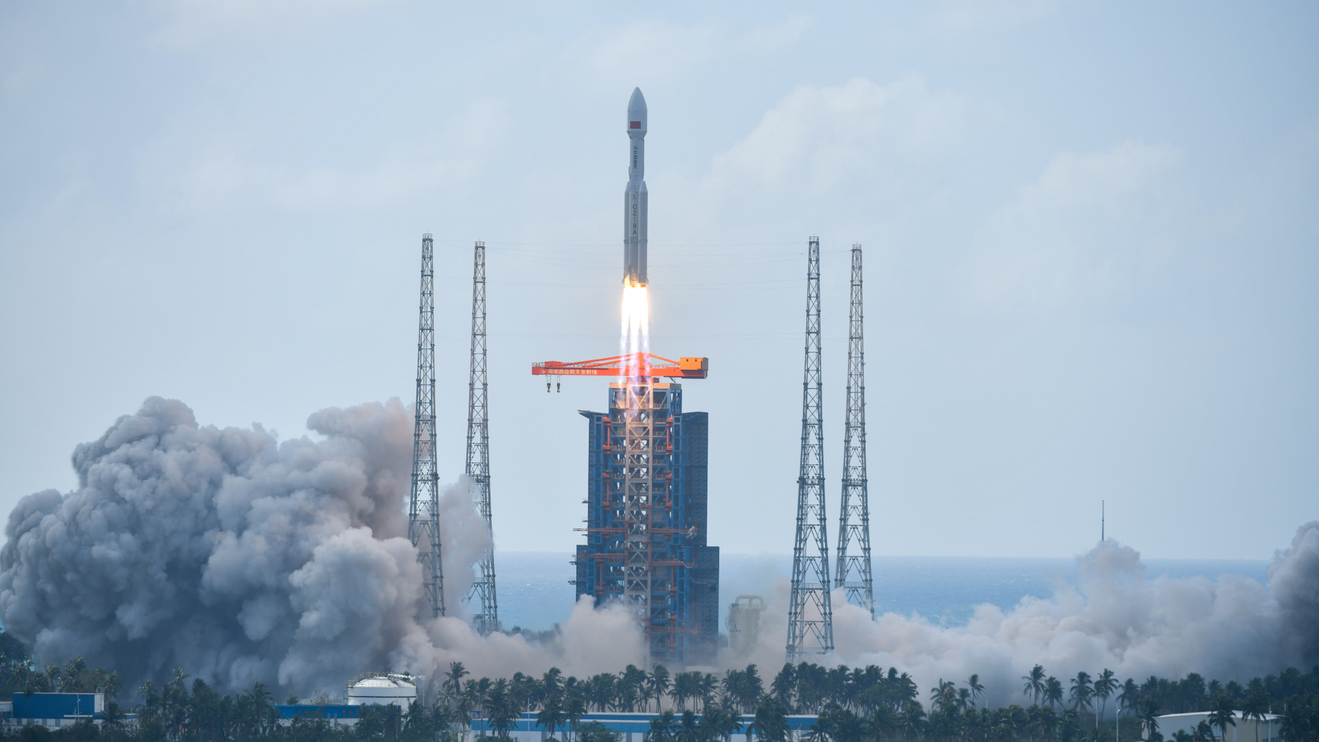 A rocket launches from a large launchpad with smoke billowing all around