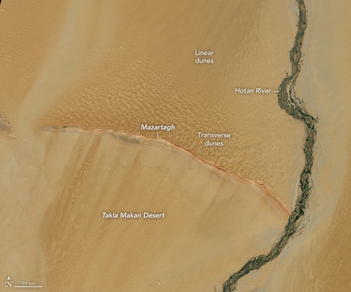 An image of Earth from space, with bright brown land streaked with a dark green river on the right side of the image with a curved ridge from left to right meeting the river toward the bottom of the image