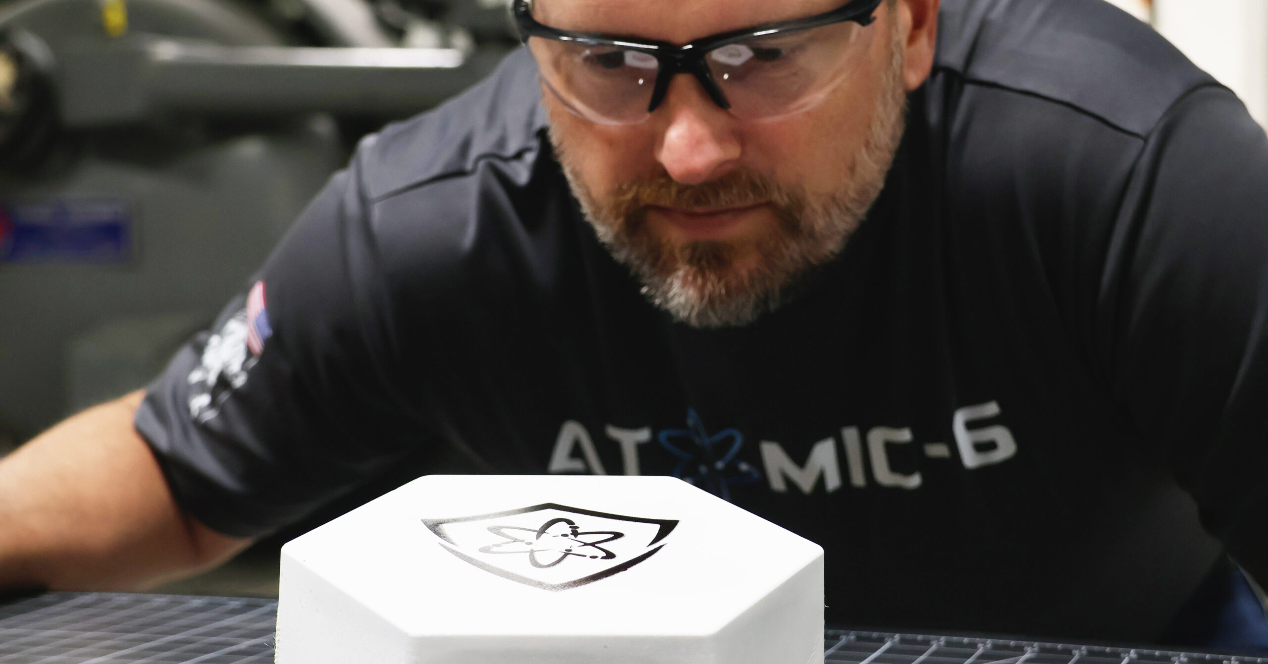 A man wearing safety glasses stands behind a hexagonal white tall tile block