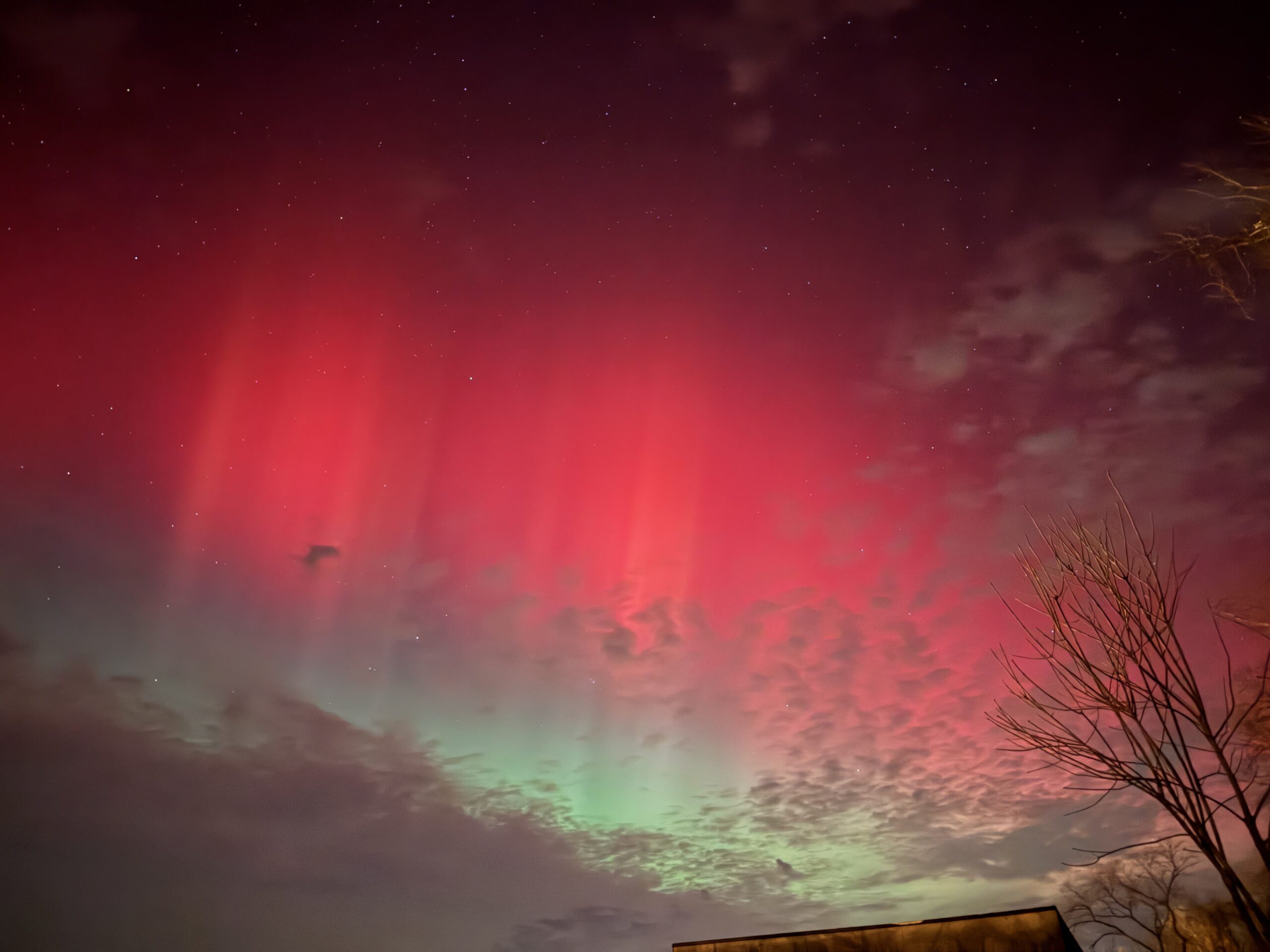 northern lights appear as curtains of red and green light in the sky.