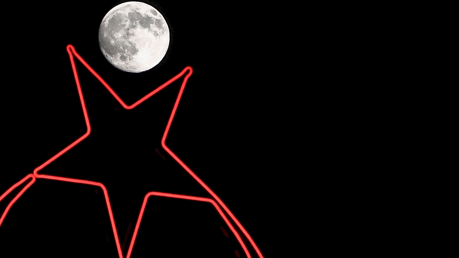 A bright near-full moon is pictured rising against a black sky above a red neon star.