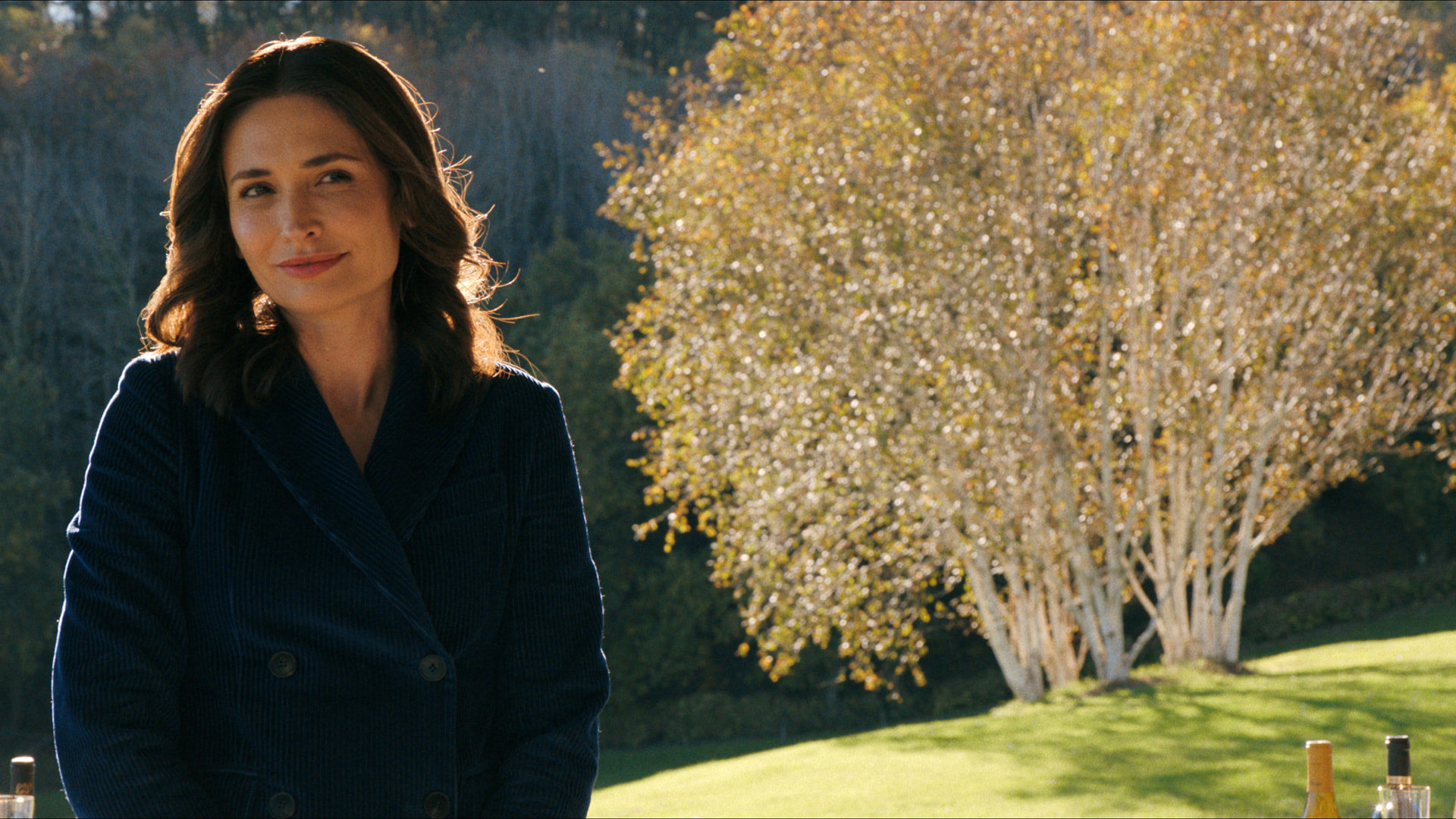 a woman smiles in a placid setting with a blossoming tree
