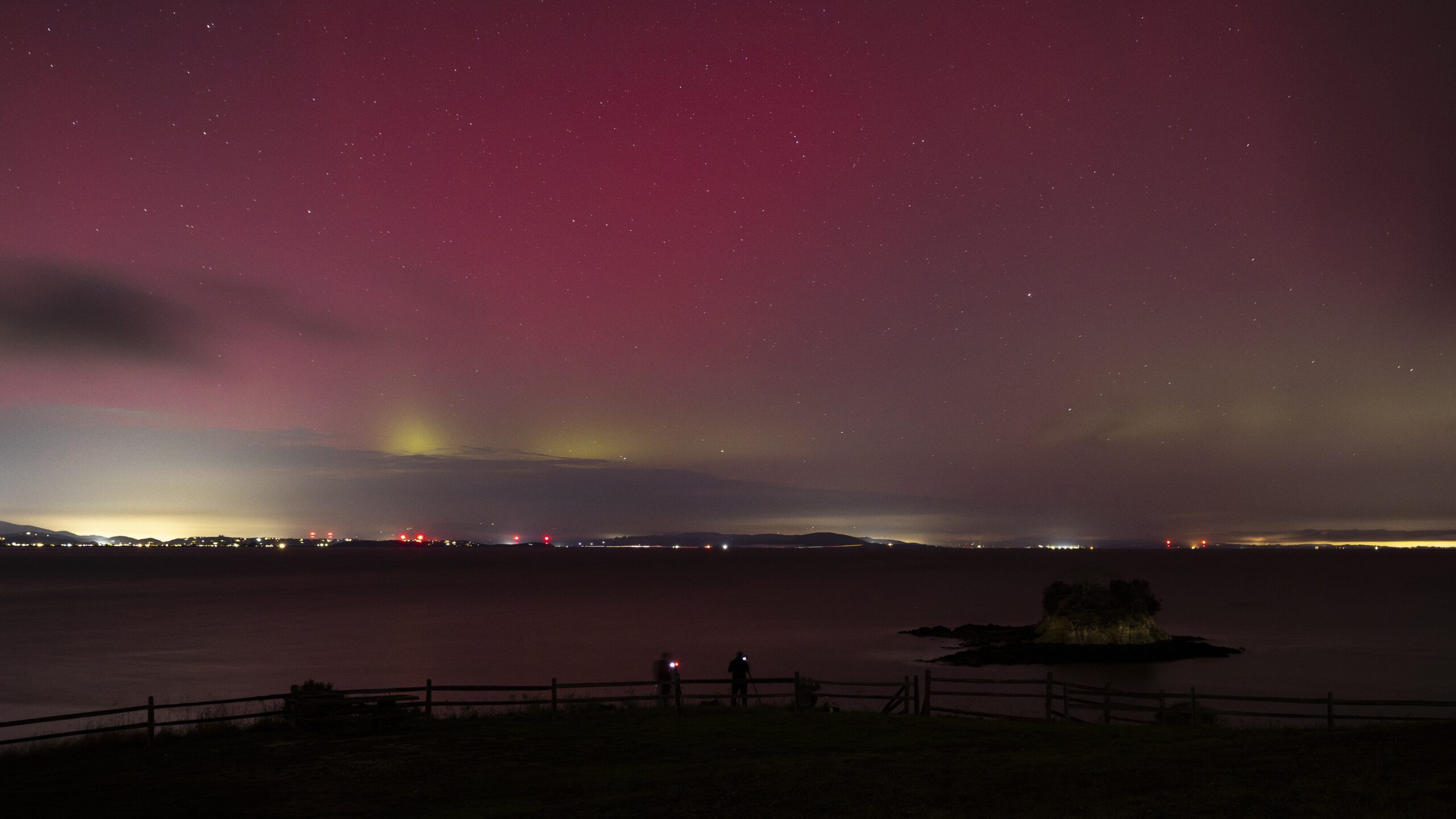 the northern lights appear as vibrant red and green curtains filling the night sky.