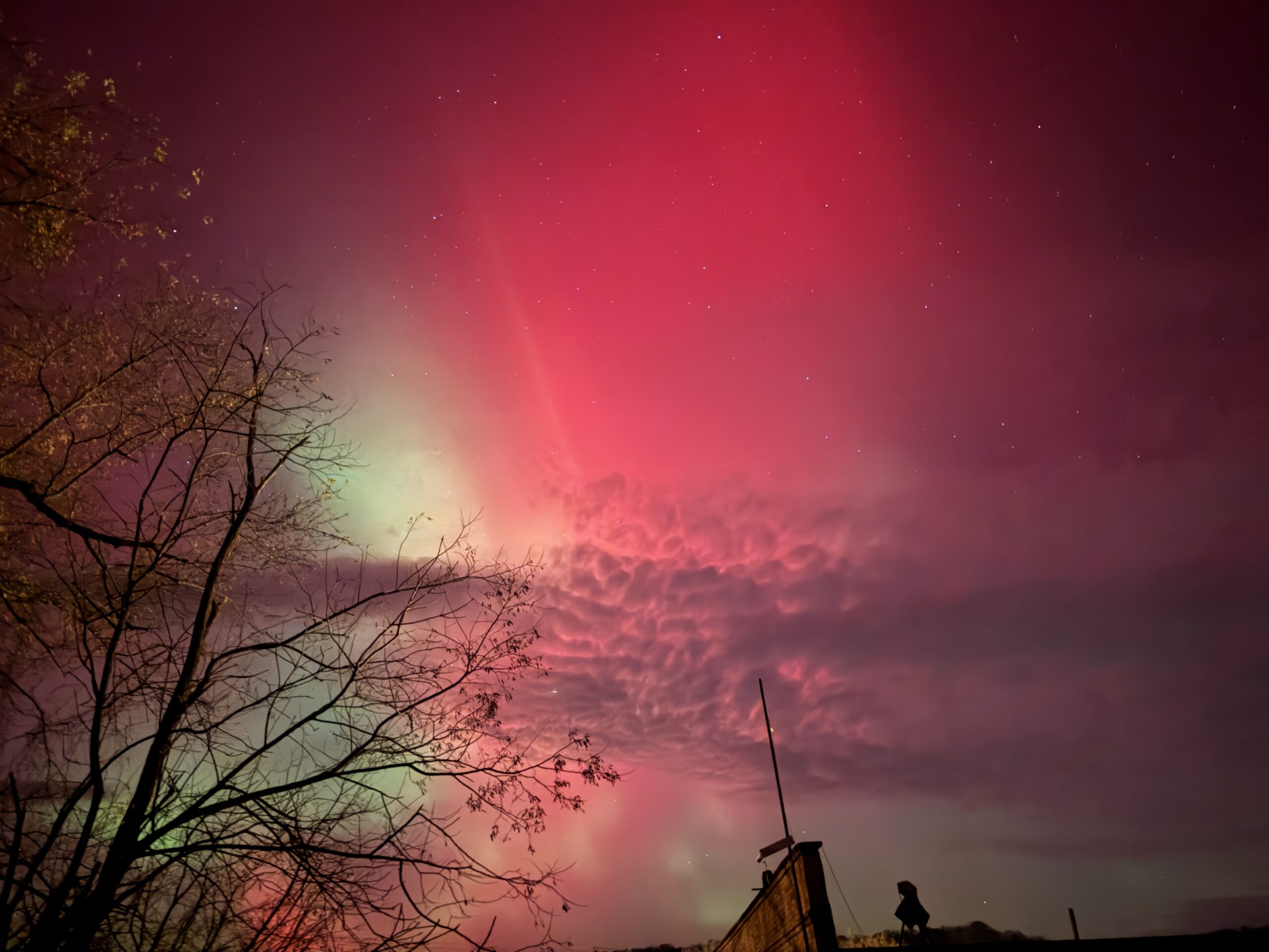 northern lights appear as curtains of red and green light in the sky.
