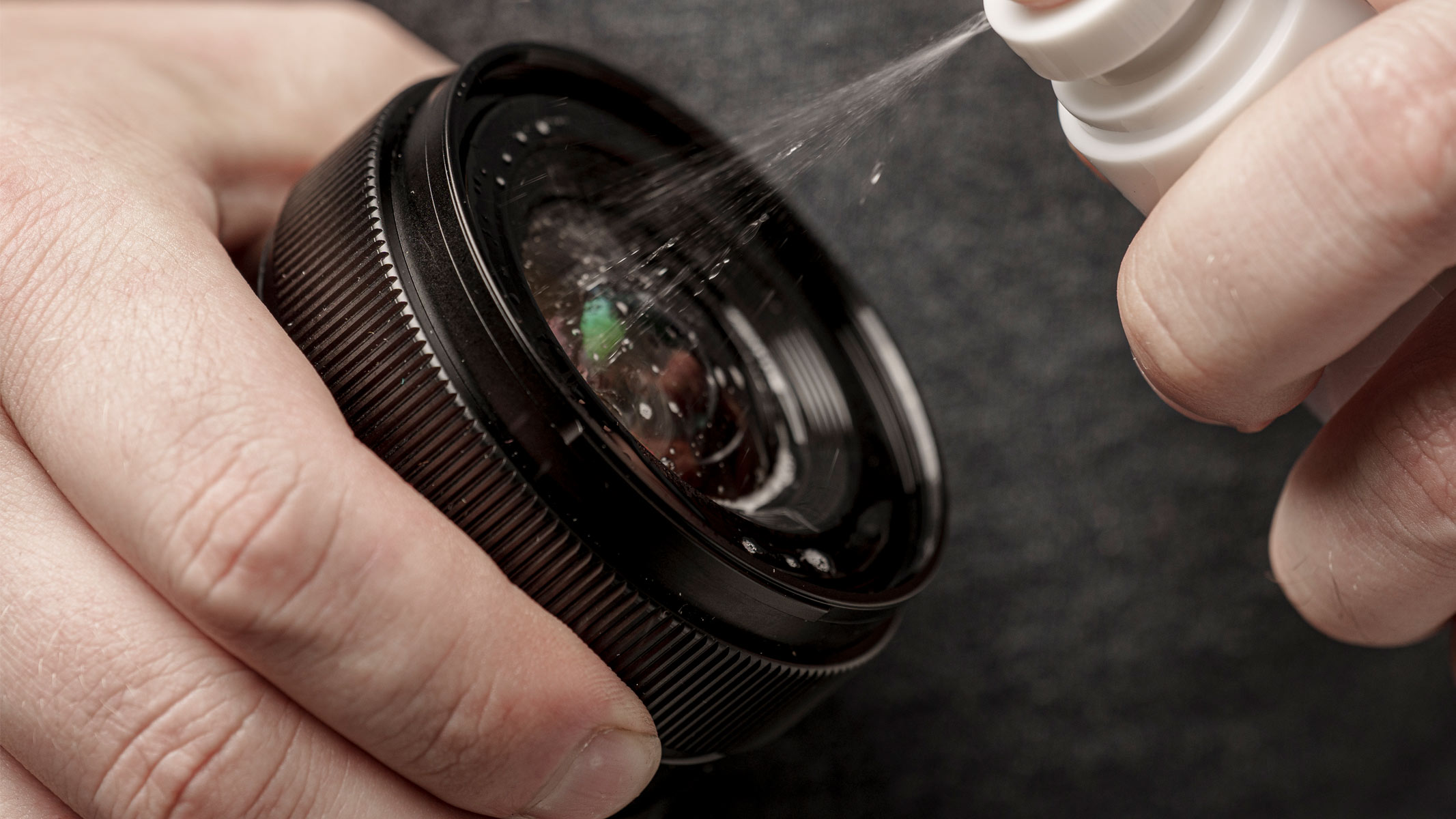A cleaning solution being sprayed onto a camera lens.