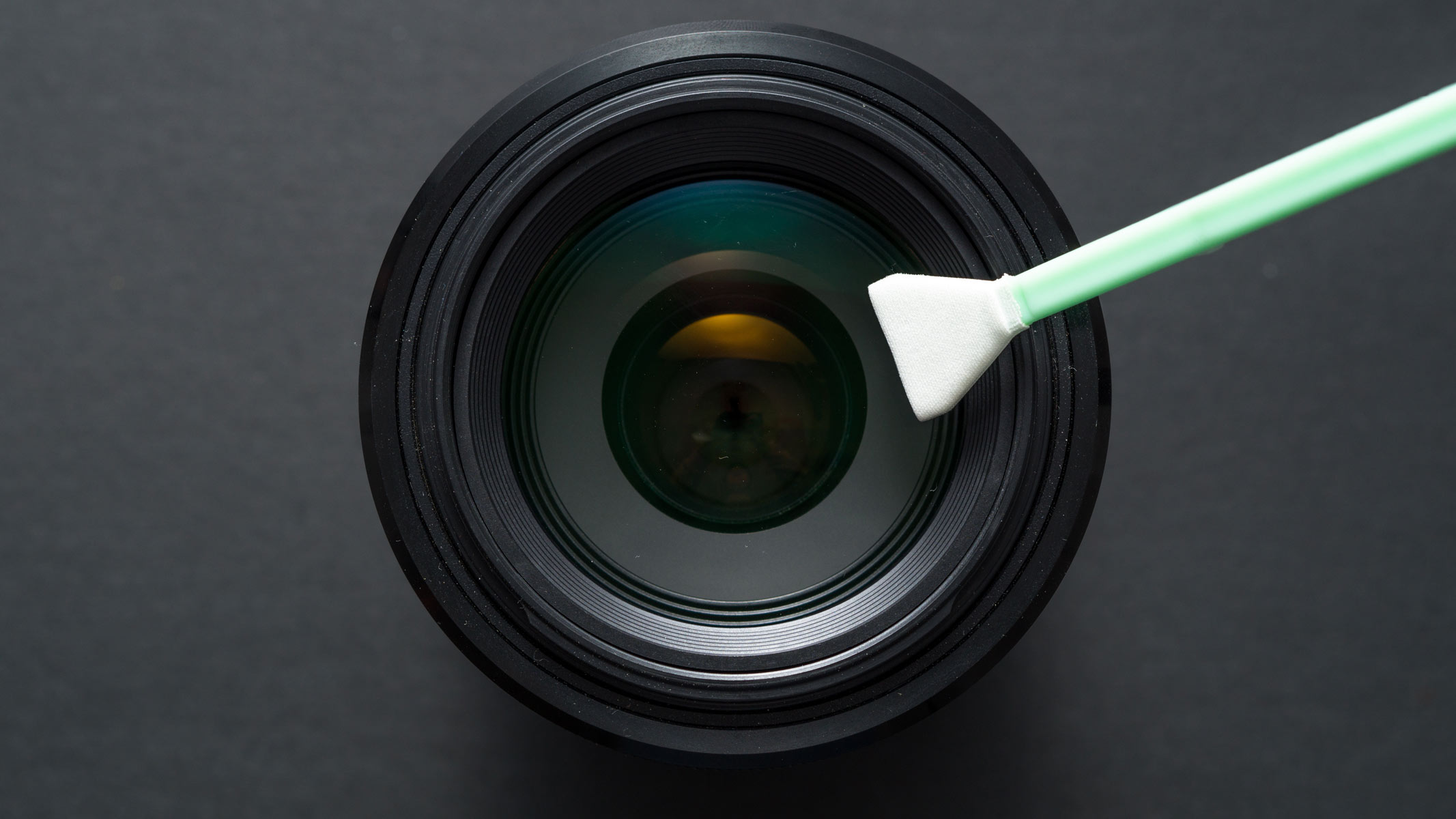 A camera lens being cleaned by a brush.