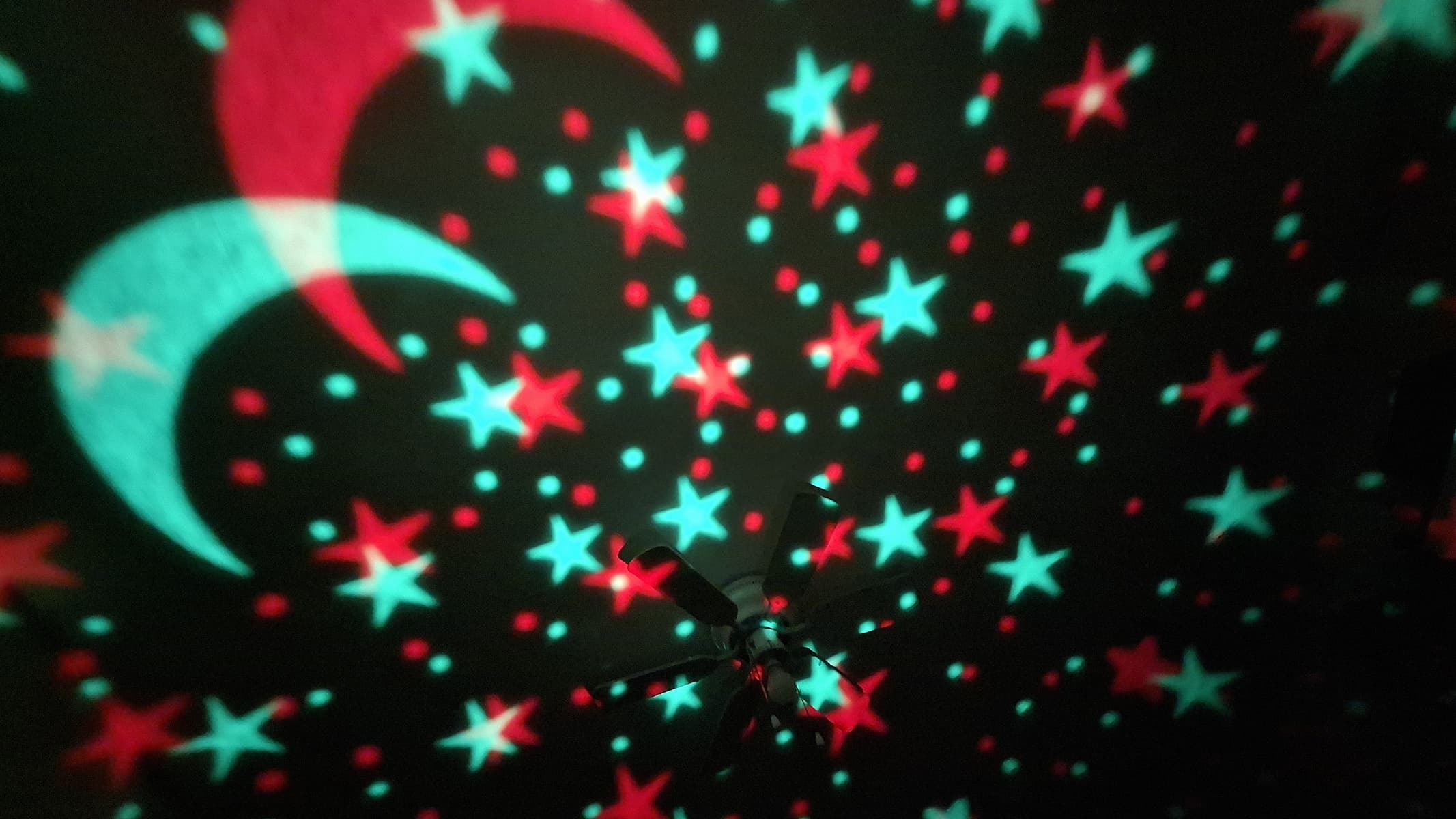 Red and green stars and moons projected from a Yachance Night Light star projector.