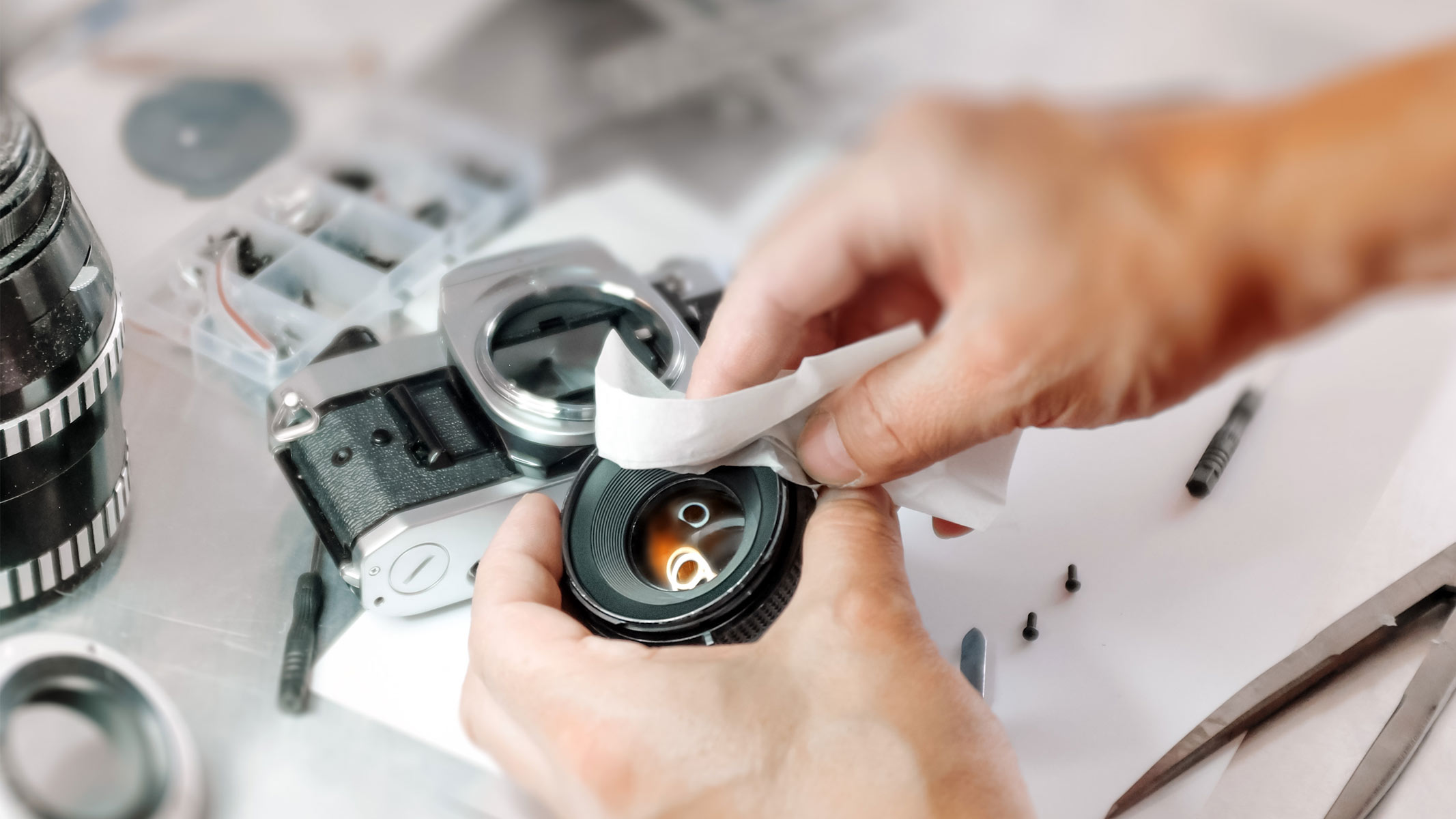 A person using a wipe to clean a camera lens.