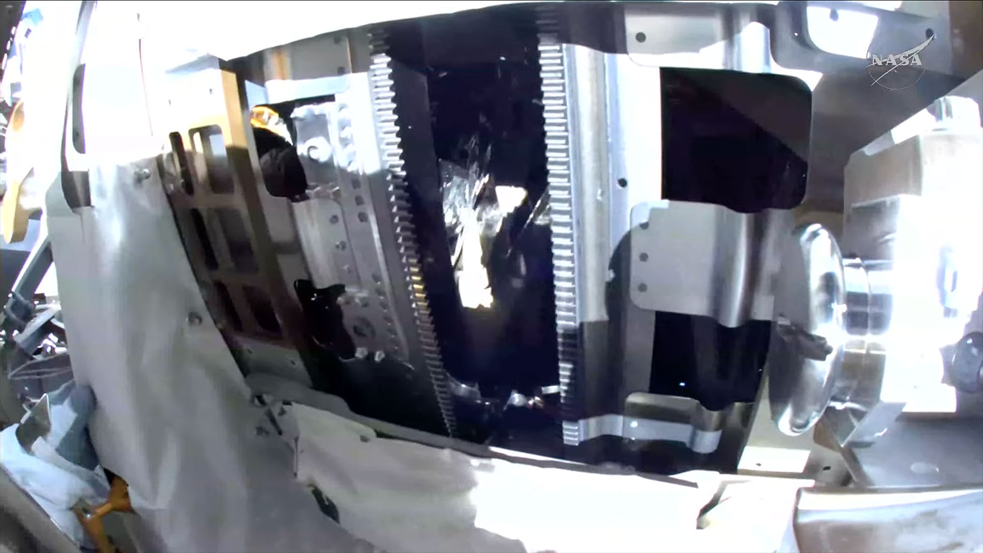 a view from a spacesuit helmet-mounted camera showing the gears for a space station's rotating solar arrays