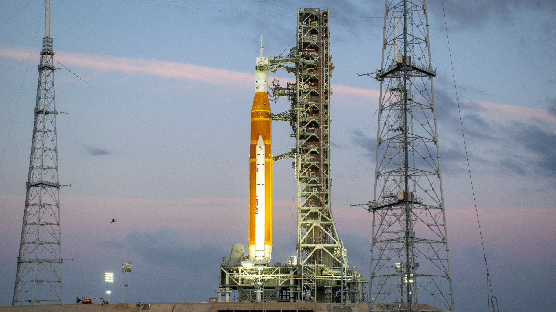 a large orange rocket upright on a launch pad