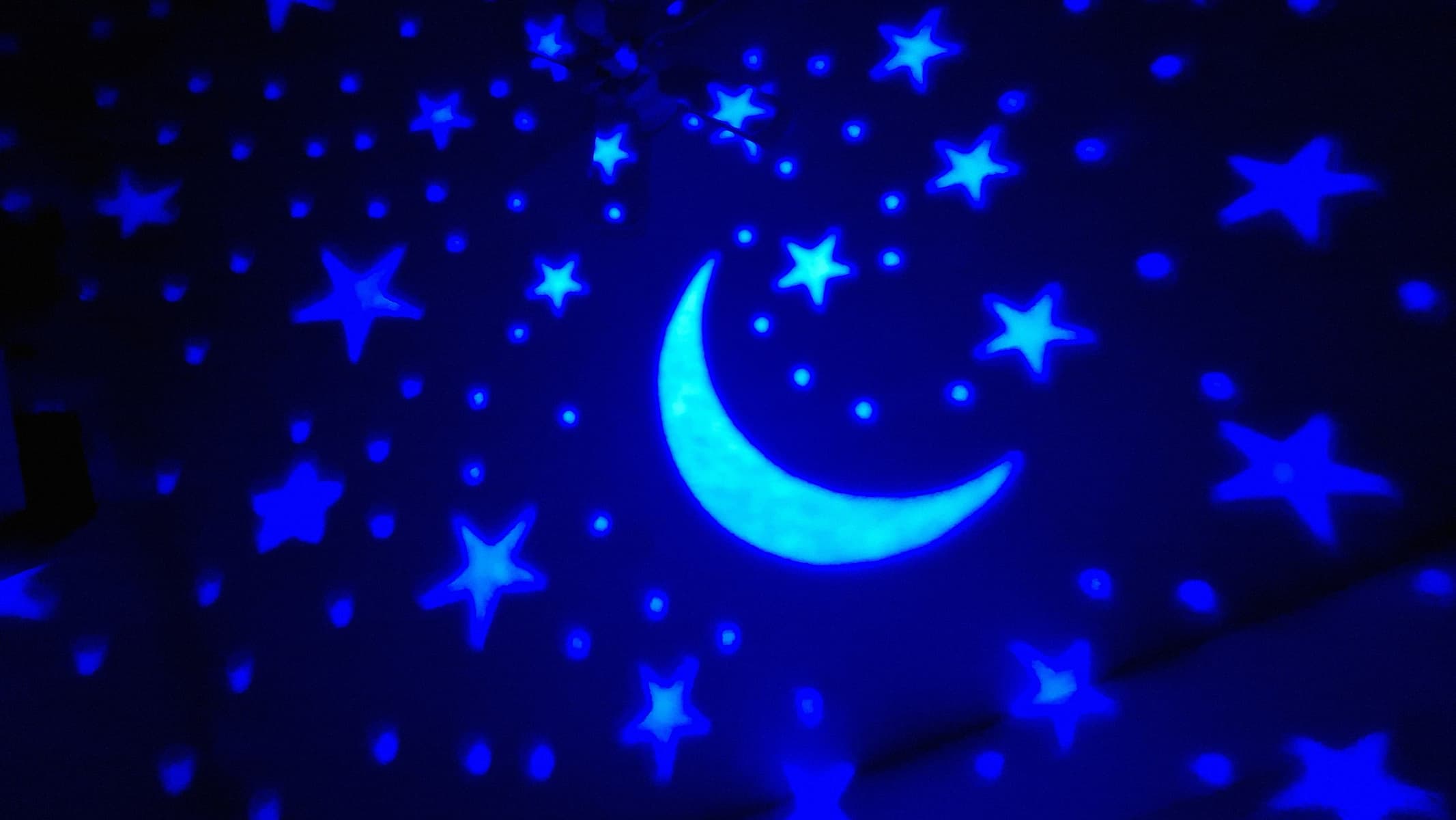 Blue stars and moons projected by a Yachance Night Light star projector.