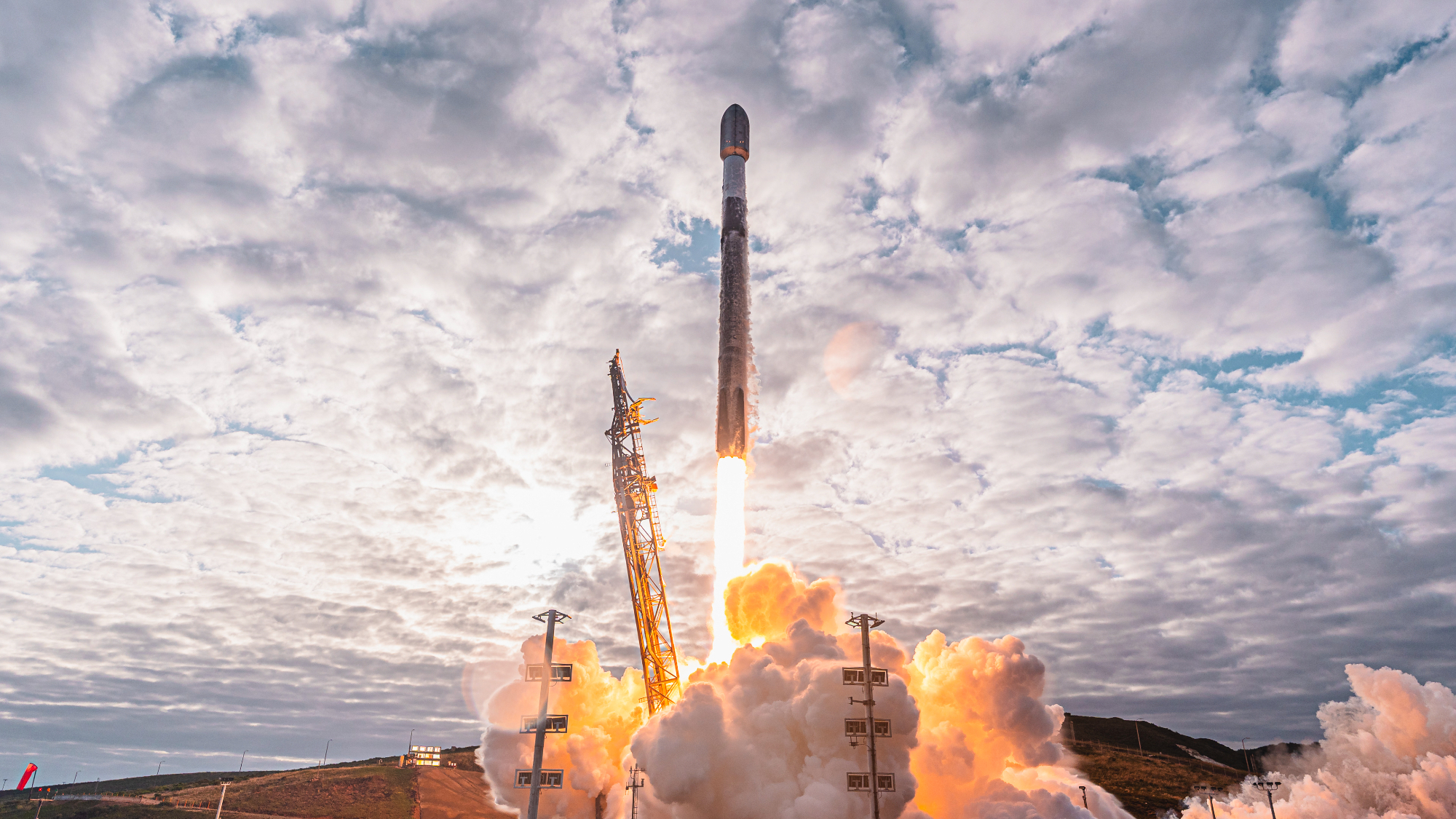 a black and white rocket launches into a cloudy sky