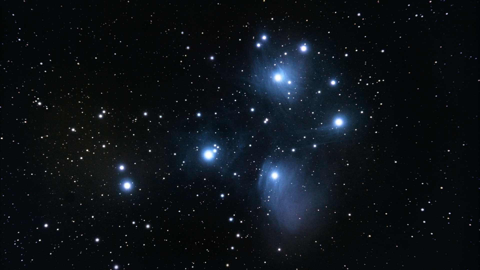 A deep space image showing the seven most prominent blue-white stars of the Pleiades star cluster shining against the blackness of space, with dimmer stars visible beyond.