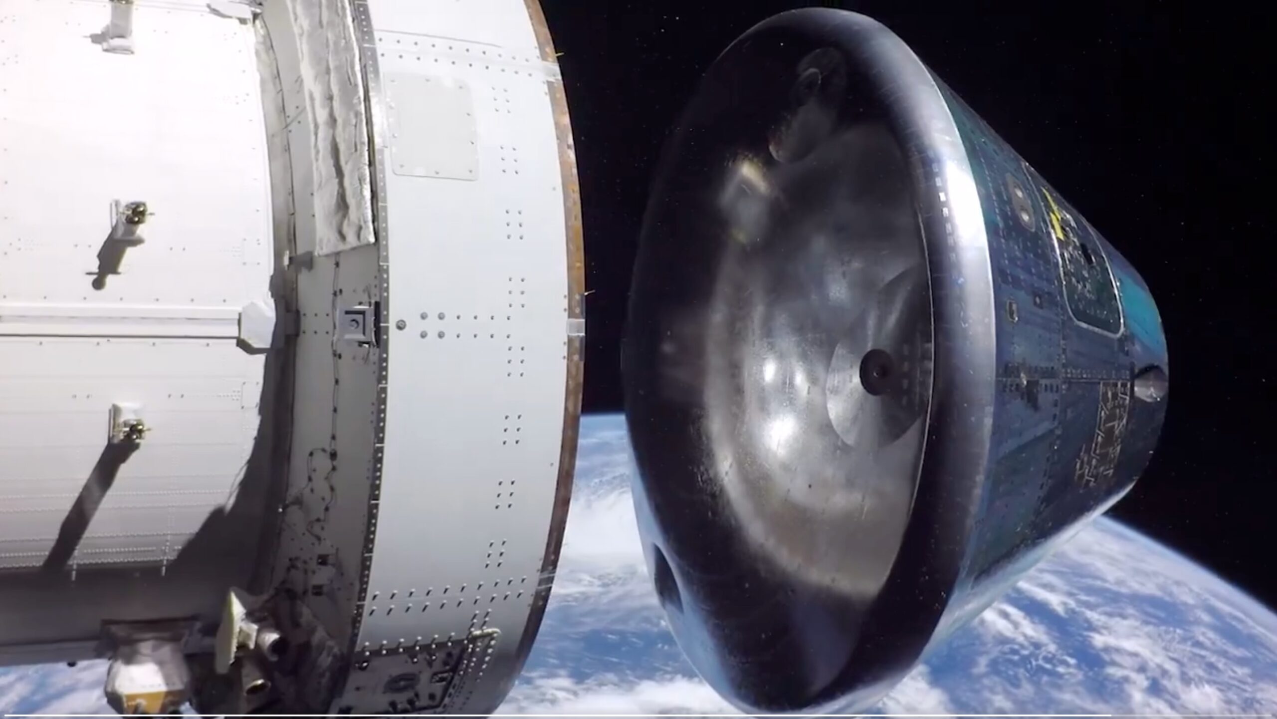 photo showing a silver, conical spacecraft separating from a white service module with earth in the background
