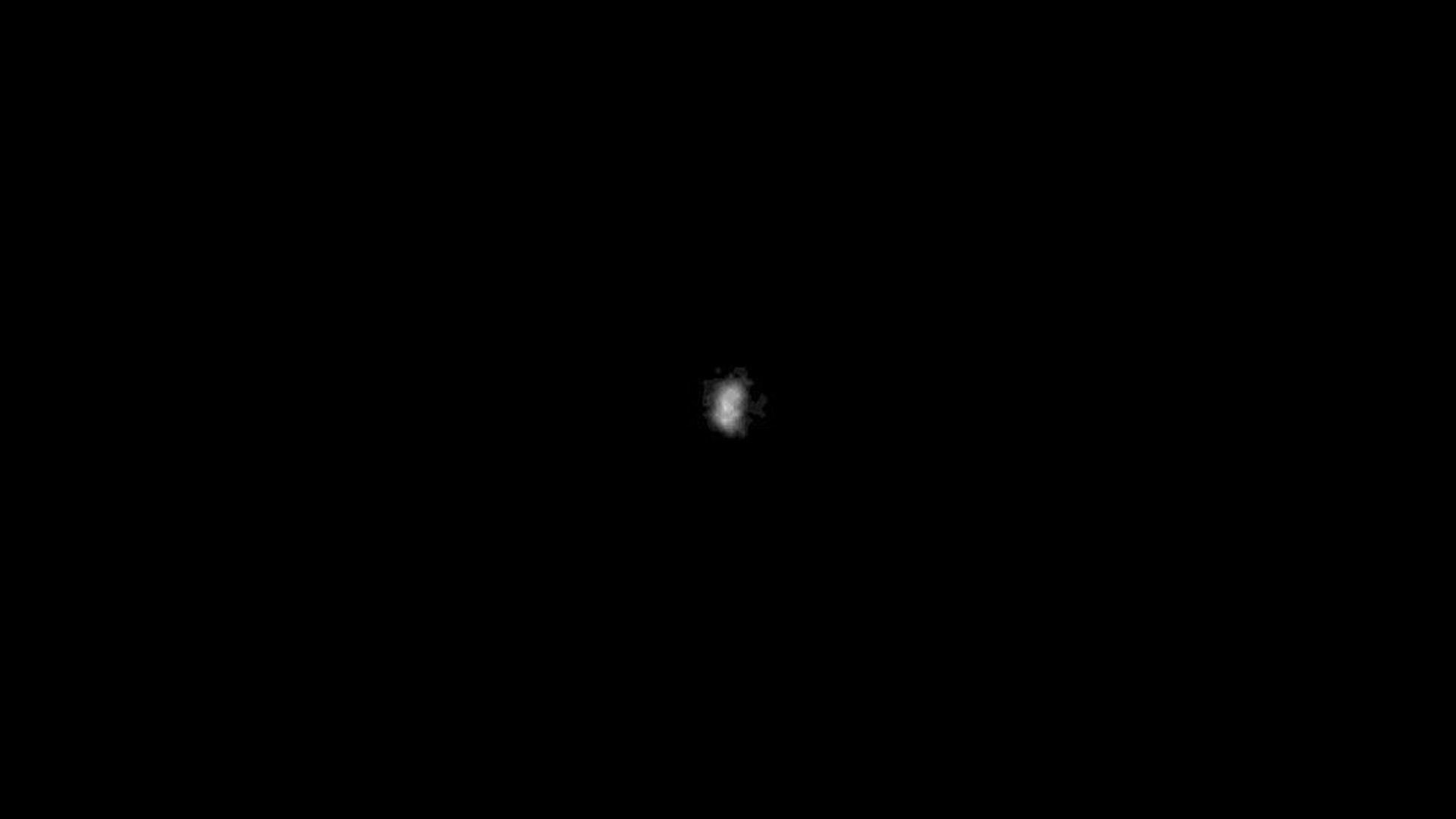 A small, fuzzy moon is in the center of a black space background.