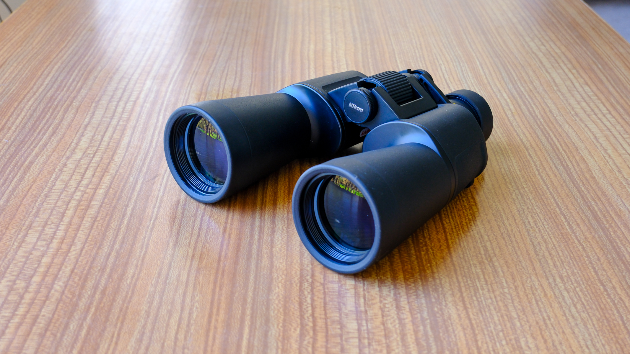 The Nikon Action 7x50 binoculars on a wooden table.