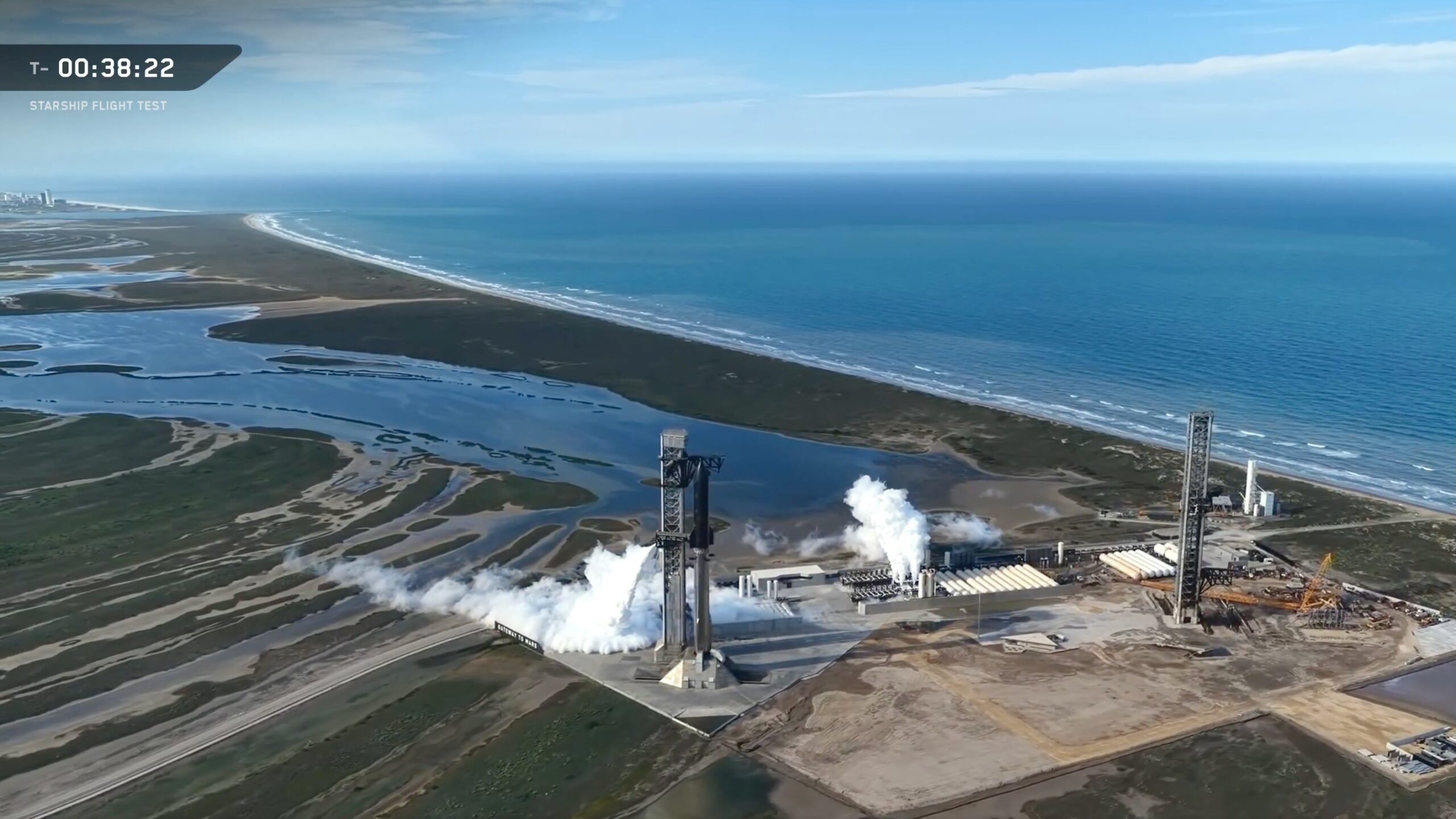 aerial view of a giant rocket on a seaside pad